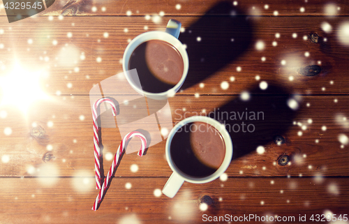 Image of christmas candy canes and cups on wooden table