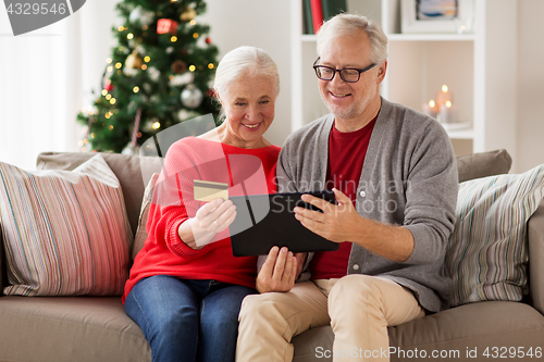 Image of happy senior couple with tablet pc at christmas