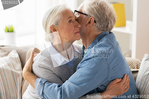 Image of sad senior couple hugging at home