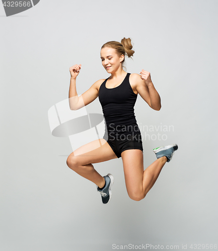 Image of young woman in black sportswear jumping