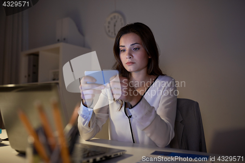 Image of businesswoman with smartphone and laptop at office