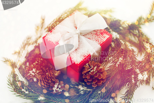 Image of christmas gift and fir wreath with cones on snow