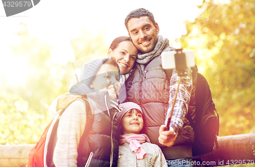 Image of happy family with smartphone selfie stick in woods