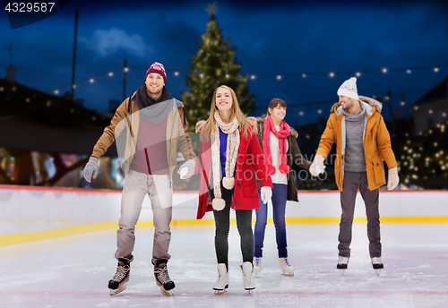 Image of happy friends on christmas skating rink