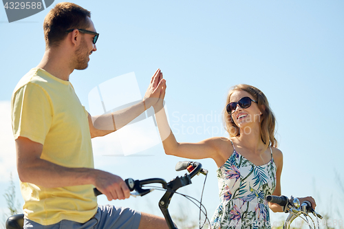 Image of happy couple with bicycles making high five