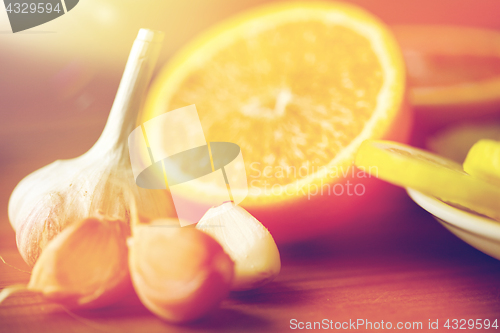 Image of close up of garlic and orange on wooden table