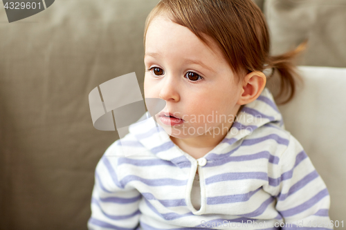 Image of portrait of baby girl sitting on sofa at home