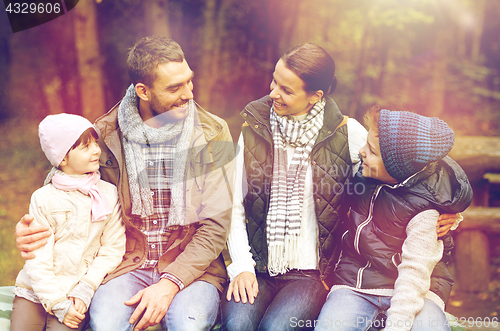 Image of happy family sitting on bench and talking at camp
