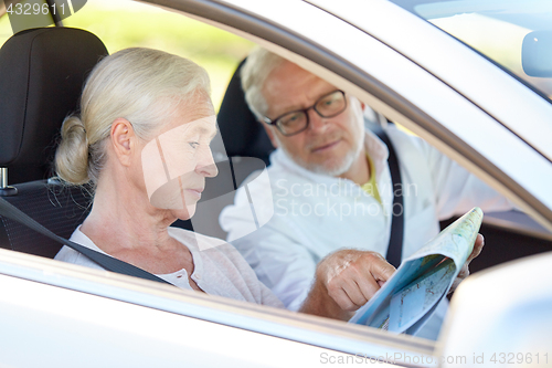 Image of happy senior couple with map driving in car