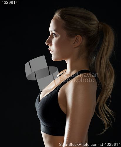 Image of young woman in black sportswear posing in gym