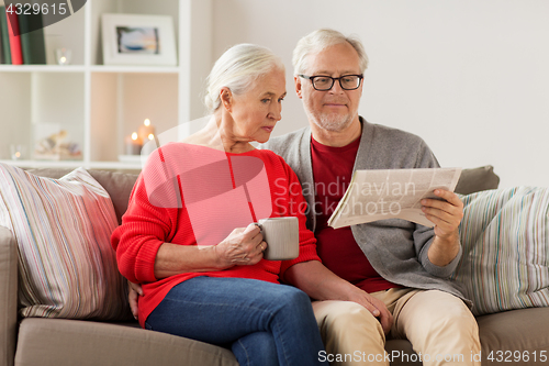 Image of happy senior couple reading newspaper at christmas