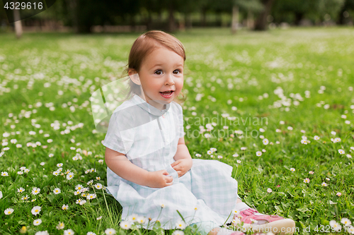 Image of happy baby girl on green summer field