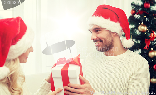 Image of happy couple at home with christmas gift box