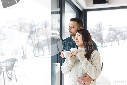 Image of multiethnic couple enjoying morning coffee by the window