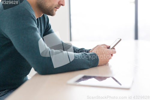 Image of Young casual businessman using smartphone