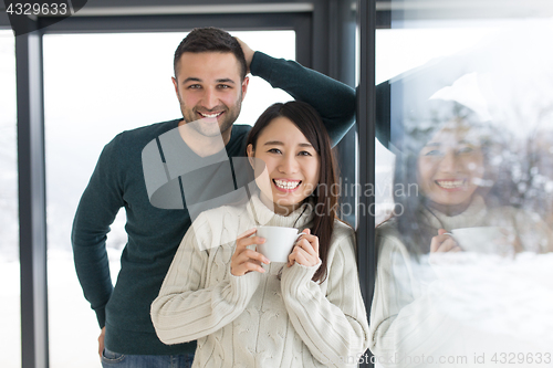 Image of multiethnic couple enjoying morning coffee by the window