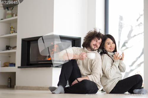 Image of happy multiethnic couple  in front of fireplace