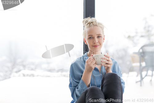 Image of woman drinking coffee and using laptop at home