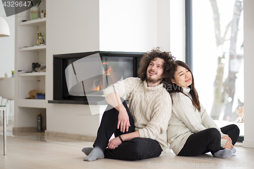 Image of happy multiethnic couple  in front of fireplace