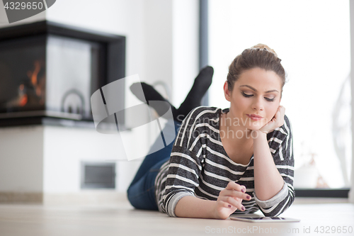 Image of woman using tablet computer in front of fireplace