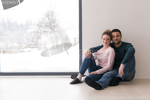 Image of young couple sitting on the floor near window at home