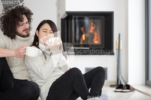 Image of happy multiethnic couple  in front of fireplace