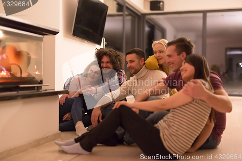 Image of multiethnic couples sitting in front of fireplace