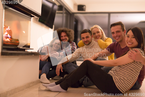 Image of multiethnic couples sitting in front of fireplace