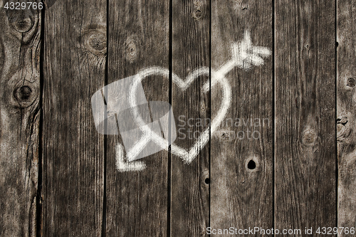 Image of painted heart with arrow on old wooden planks