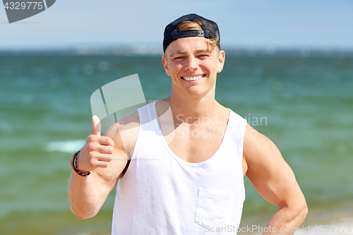 Image of smiling man showing thumbs up on summer beach