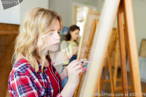 Image of student girl with easel painting at art school