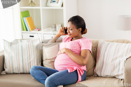 Image of happy pregnant woman calling on smartphone at home