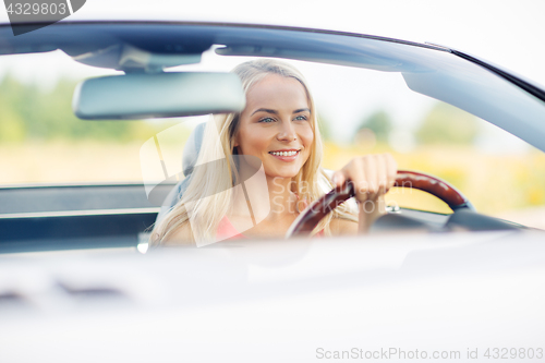 Image of happy young woman driving convertible car