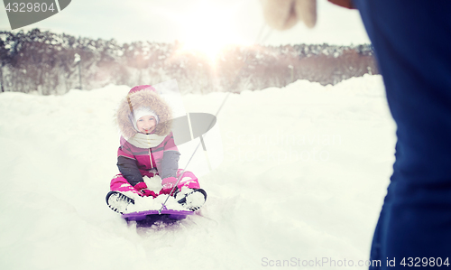 Image of parent carrying happy little kid on sled in winter