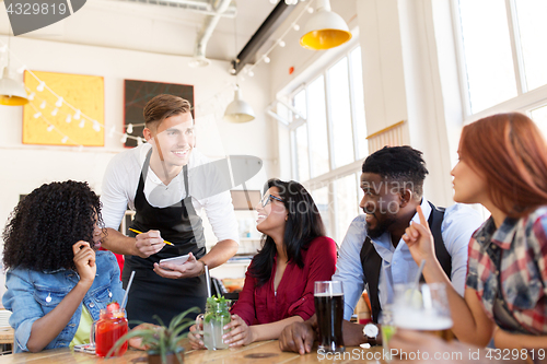 Image of waiter and friends with menu and drinks at bar