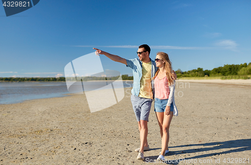 Image of happy couple walking along summer beach