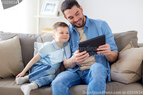 Image of father and son with tablet pc playing at home