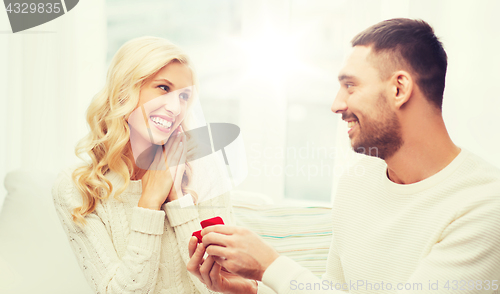 Image of happy man giving engagement ring to woman at home