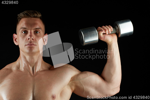 Image of man with dumbbell exercising over black background