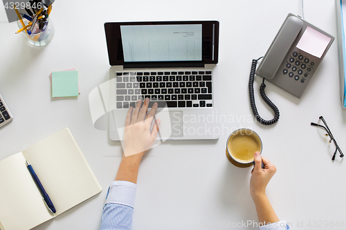 Image of businesswoman with laptop and coffee at office