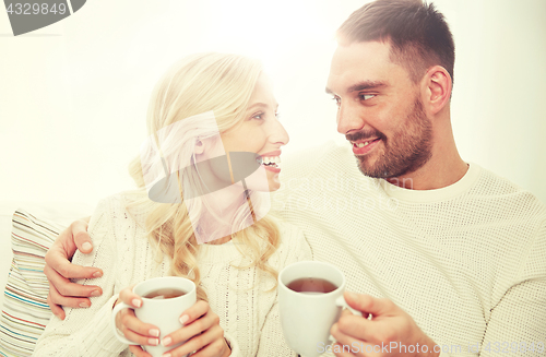 Image of happy couple with cups drinking tea at home