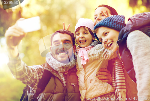 Image of family taking selfie with smartphone outdoors