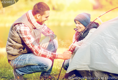 Image of happy father and son setting up tent outdoors