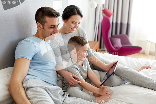 Image of happy family with tablet pc in bed at home