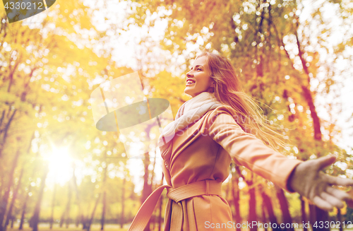 Image of beautiful happy young woman walking in autumn park