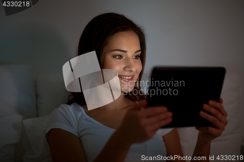 Image of young woman with tablet pc in bed at home bedroom