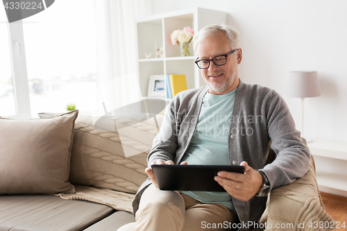 Image of senior man with tablet pc sitting on sofa at home