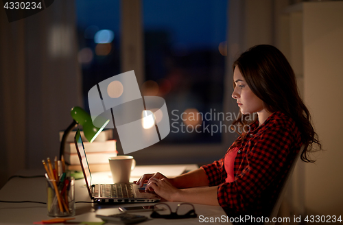 Image of student or woman typing on laptop at night home