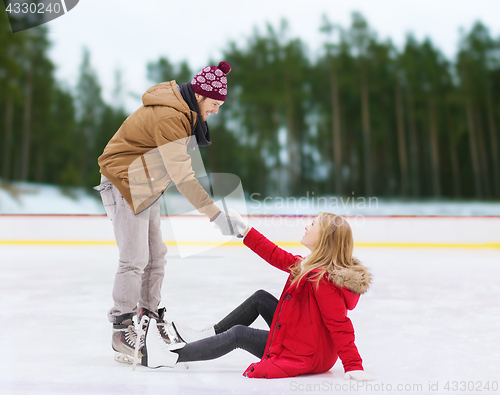 Image of man helping woman to rise up on skating rink
