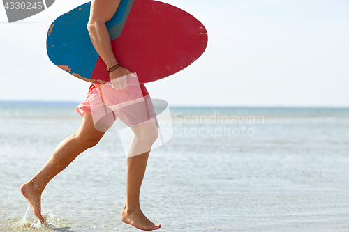 Image of young man with skimboard on summer beach